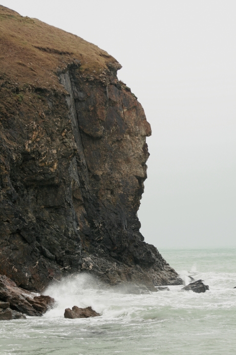 Photograph of a stack just off shore, showing steep cliff faces on all sides