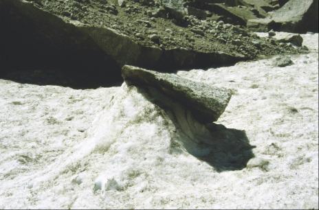 photo of a rock protecting snow beneath it from insolation, whilst surrounding snow has melted