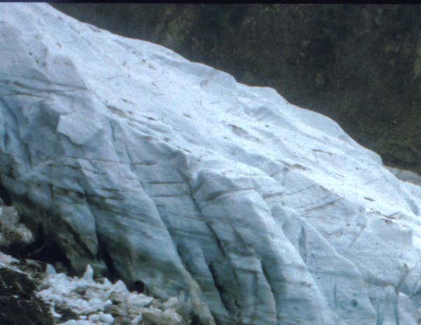 Photo of a glacier with dark lines of debris indicating shere planes within the ice